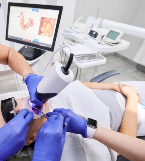 Dentist and his assistant scanning patient's teeth with modern scanning machine. Digital print of patient's teeth is on big screen. Modern high precision technologies. Concept of modern dentistry